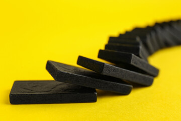 Sticker - Falling black domino tiles on yellow background, closeup