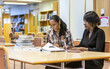© track5 - Teenage Students, research library. A pair of late-teenage college friends working together in their school library. From a series of related images.