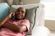 © Wavebreak Media - Happy african american male teenager talking on smartphone and lying on couch