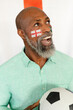 Happy senior african american man sitting with flag of england and football