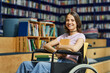 © Seventyfour - Vibrant portrait of young female student with disability looking at camera in college library and smiling