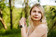 © brillianata - Beautiful young blonde in the forest. The girl enjoys nature on a summer sunny day against the background of green trees. Close portrait