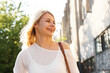 © brillianata - Happy blonde woman on the city street with old buildings and trees. Summer sunny day