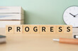 © ELUTAS - 進歩・発展のイメージ｜「PROGRESS」と書かれたブロックが置かれたデスク
