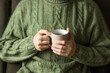 © Kseniia - Married man wearing green knitted woolen sweater holding hot cup of tea in the cold autumn or winter morning.