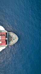 Wall Mural - Aerial top vertical view of a big cargo container vessel sailing with speed over blue sea