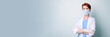 © Galina - Young woman in white medical gown and protective mask stands with her arms folded on her chest. Portrait of female doctor on gray monochrome background. Banner with free space for text