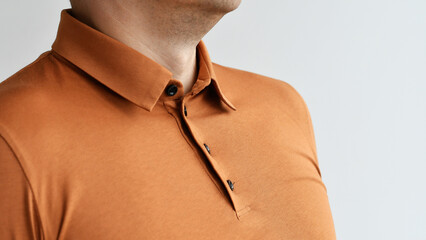 Fragment of man wearing dark beige polo. Selective focus.