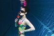 beautiful woman in a colourful stylish swimsuit and sunglasses and pink gerbera in the head with a cocktail  in her hand underwater in the swimming pool