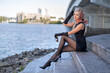 © Taranukhin Alex - Beautiful blonde girl in black dress with perfect legs in pantyhose and shoes with high heels posing outdoor near the river bridge in the rays of sun. Street fashion photo.