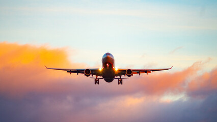 the silhouette of a passenger plane coming in for landing against the backdrop of the sunset sky.