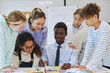 © Seventyfour - Portrait of young black teacher smiling with diverse group of children in school