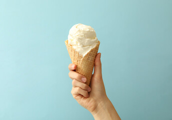 Wall Mural - woman holding waffle cone with delicious ice cream on light blue background, closeup