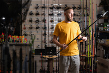 Man Shopper Choosing Fishing Rod In Fishing Store