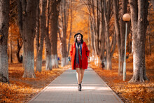 Autumn Season. Elegant Beautiful Mature Caucasian Woman In A Red Coat And Hat Walks Along The Path Of The Autumn Park. Copy Space