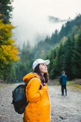 Poster - woman in yellow raincoat hiker in autumn mountains