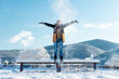 A happy young woman is standing on a bench with snow thrown on top. Winter Christmas holidays