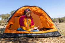 Woman Sitting In Her Tent Writing Notes On Notebook