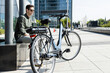 © ADDICTIVE STOCK - Trendy man sitting with bike in downtown