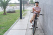 © ADDICTIVE STOCK - Positive Latin man browsing smartphone on bicycle