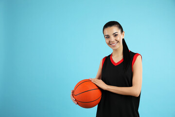 Wall Mural - Basketball player with ball on light blue background. Space for text