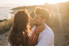Loving Couple Hugging And Looking At Each Other On Seashore On Sunset