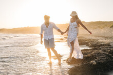Affectionate Couple Standing On Ocean Waves Holding Hands On Sunset