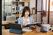© Nuttapong punna - Young beautiful woman using laptop and tablet while sitting at her working place. Concentrated at work..