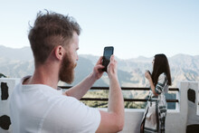 Man Taking Mobile Photos Of His Girlfriend In A Mountainous Landscape