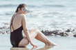 © ADDICTIVE STOCK - Thoughtful young woman in sunglasses sitting on the seashore