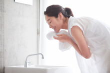洗面所で顔を洗う女性