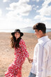 © ADDICTIVE STOCK - Smiling young ethnic couple holding hands while walking along sandy seacoast in Spain