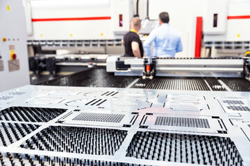 Computer numerical control programmable machine for metal, operator working in the background