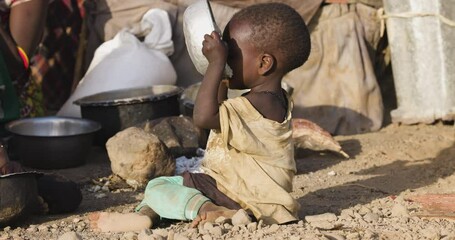 close-up. malnourished child due to extreme poverty, drought and climate change. eating and drinking
