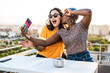 © ADDICTIVE STOCK - Happy lesbian couple taking selfie on balcony
