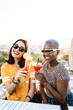 © ADDICTIVE STOCK - Multiethnic couple of cool lesbian women drinking cocktails