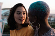 © ADDICTIVE STOCK - Multiracial lesbian couple sitting close together outdoors