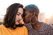 © ADDICTIVE STOCK - Multiracial lesbian couple sitting close together outdoors