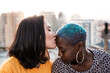 © ADDICTIVE STOCK - Multiracial lesbian couple sitting close together outdoors