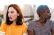 © ADDICTIVE STOCK - Multiracial lesbian couple sitting close together outdoors