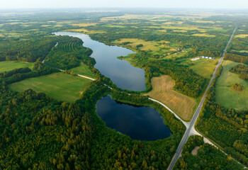 Wall Mural - Highway through forest with pine trees and lakes, aerial view. Road with forrest trees and car. Forest road for transpotrs. Aerial above view of freeway. Asphalt road near lake in village, top view.