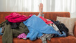 Dependence on things, conscious consumption of clothes, shopaholic, hand reaching out of a pile of clothes
