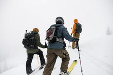 Rear View Of Group Of People Walking To The Top Of The Snow-covered Mountain