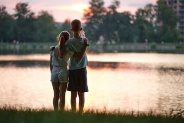 happy siblings hugging lovingly in summer park. young children brother and sister embracing each oth