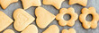 Baked shortbread heart and flower cookies on parchment paper banner. Wide panoramic header. Selective focus