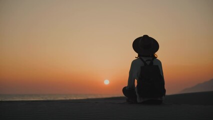 Wall Mural - Young tourist sitting on the sand and looking at the sea