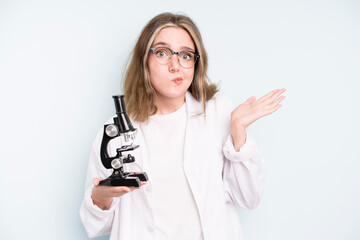 Wall Mural - caucasian pretty woman feeling puzzled and confused, scratching head. science student with a microscope