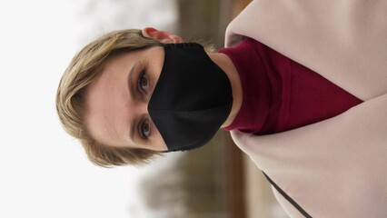 Wall Mural - health, safety and pandemic concept - young woman wearing black face protective reusable barrier mask outdoors, vertical view orientation