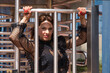 Attractive mature woman, with transparent black shirt, clinging to the metal bars of the entrance of a company in seductive attitude. Concept maturity, beauty, fashion, sensuality.
