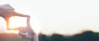 © Urupong - The woman making frame round the sun with her hands in sunrise,Future planning idea concept.